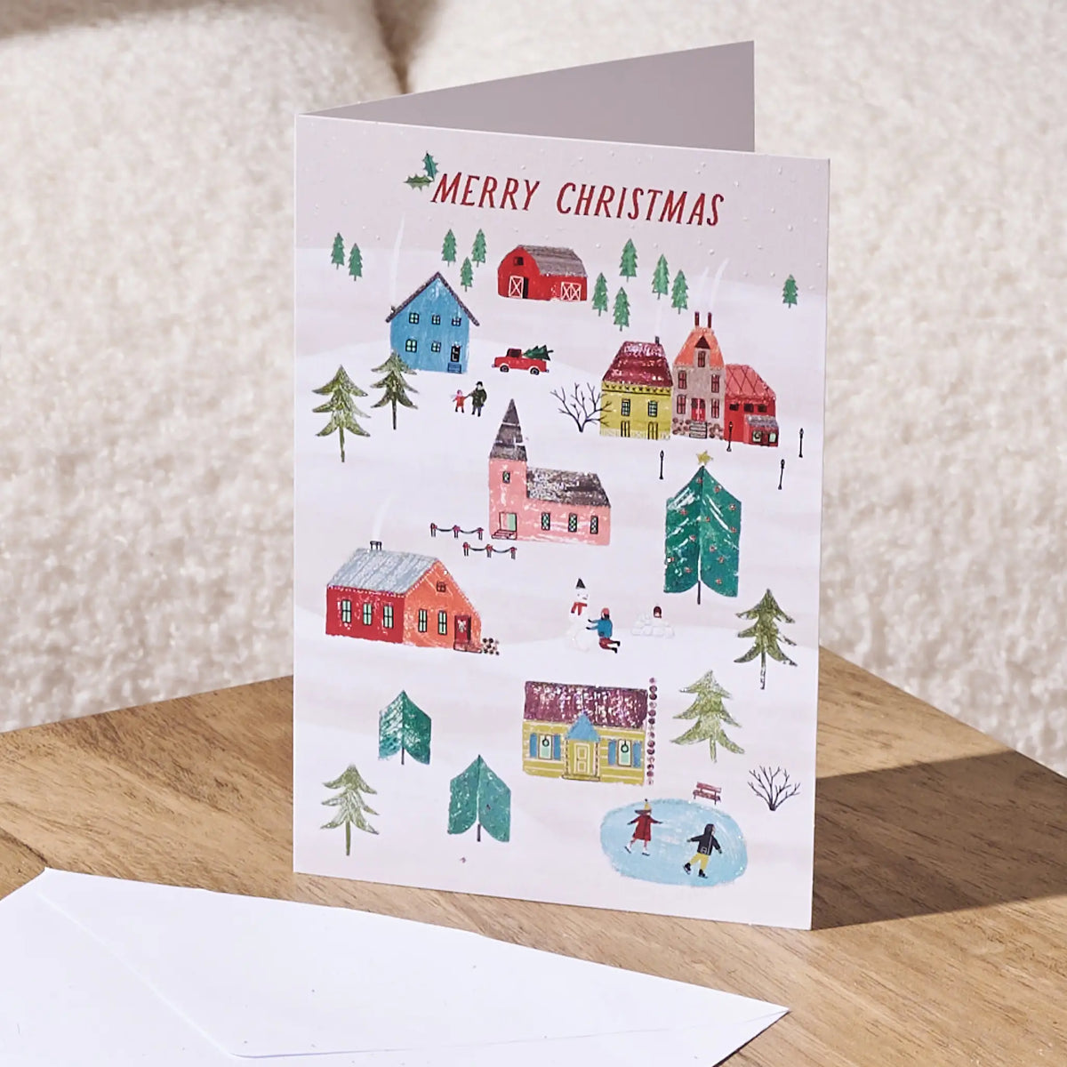 Merry Christmas greeting card on top of a table with a white envelope