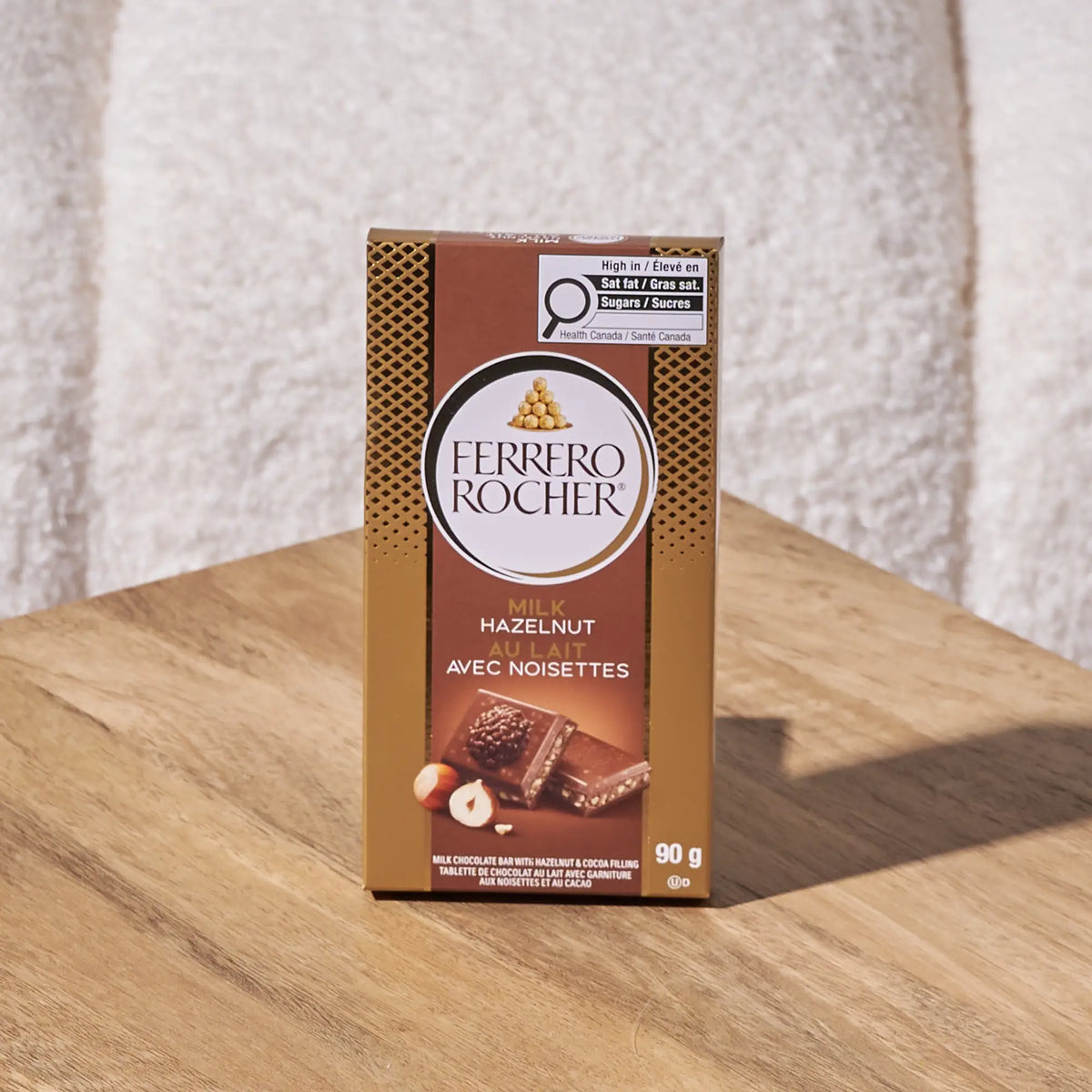 Ferrero Rocher hazelnut milk chocolate bar on a wooden surface with a textured white background