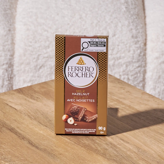 Ferrero Rocher hazelnut milk chocolate bar on a wooden surface with a textured white background