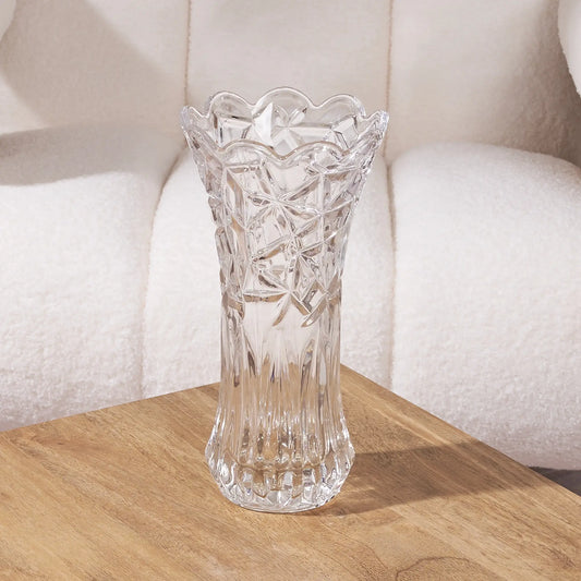 tall clear glass vase with intricate design on a wooden surface