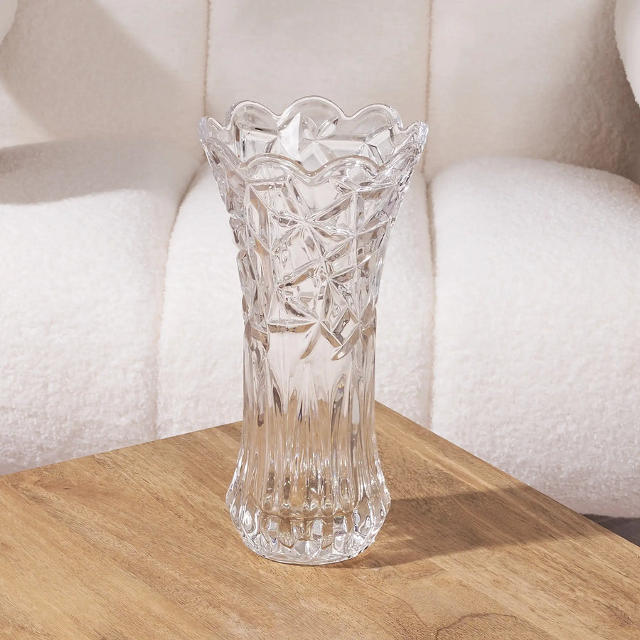 tall clear glass vase with intricate design on a wooden surface