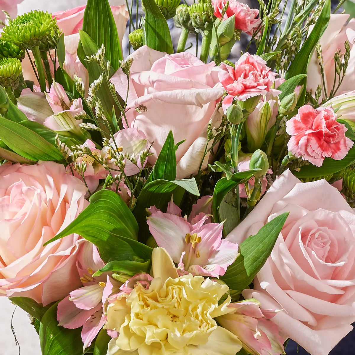 a closeup shot of Bouquet of pink and yellow flowers with green leaves