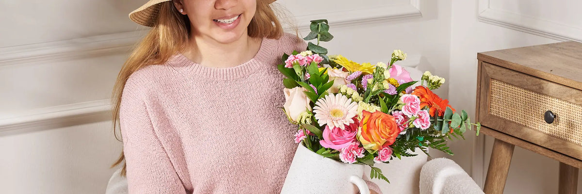 Woman holding The Clementine Mixed Rose Bouquet by Gilded Blooms in a home setting