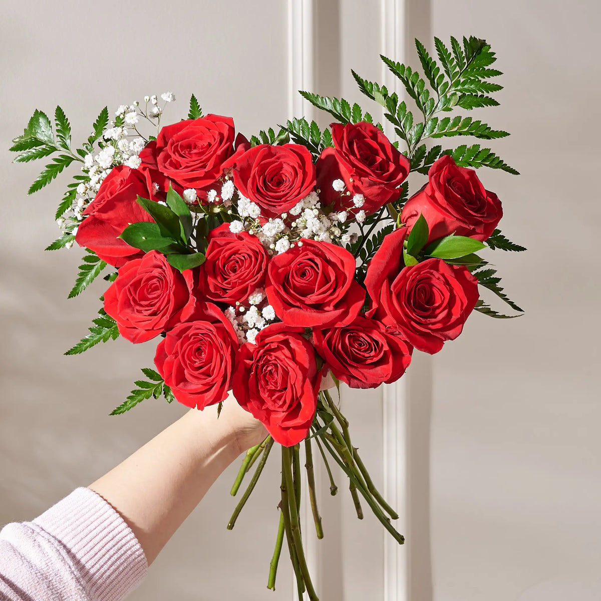 Bouquet of red roses held by a person against a neutral background