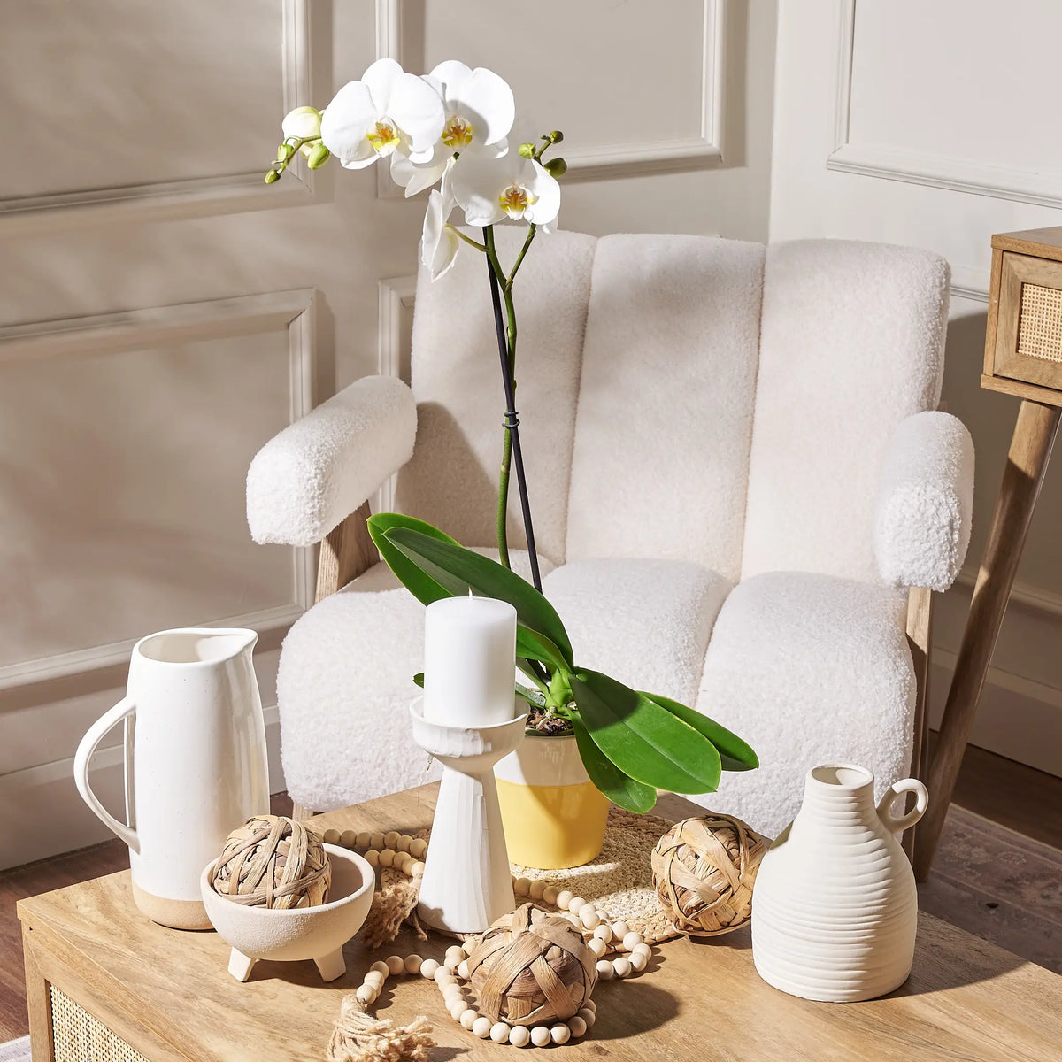 Decorative items on a wooden table with a white armchair in the background