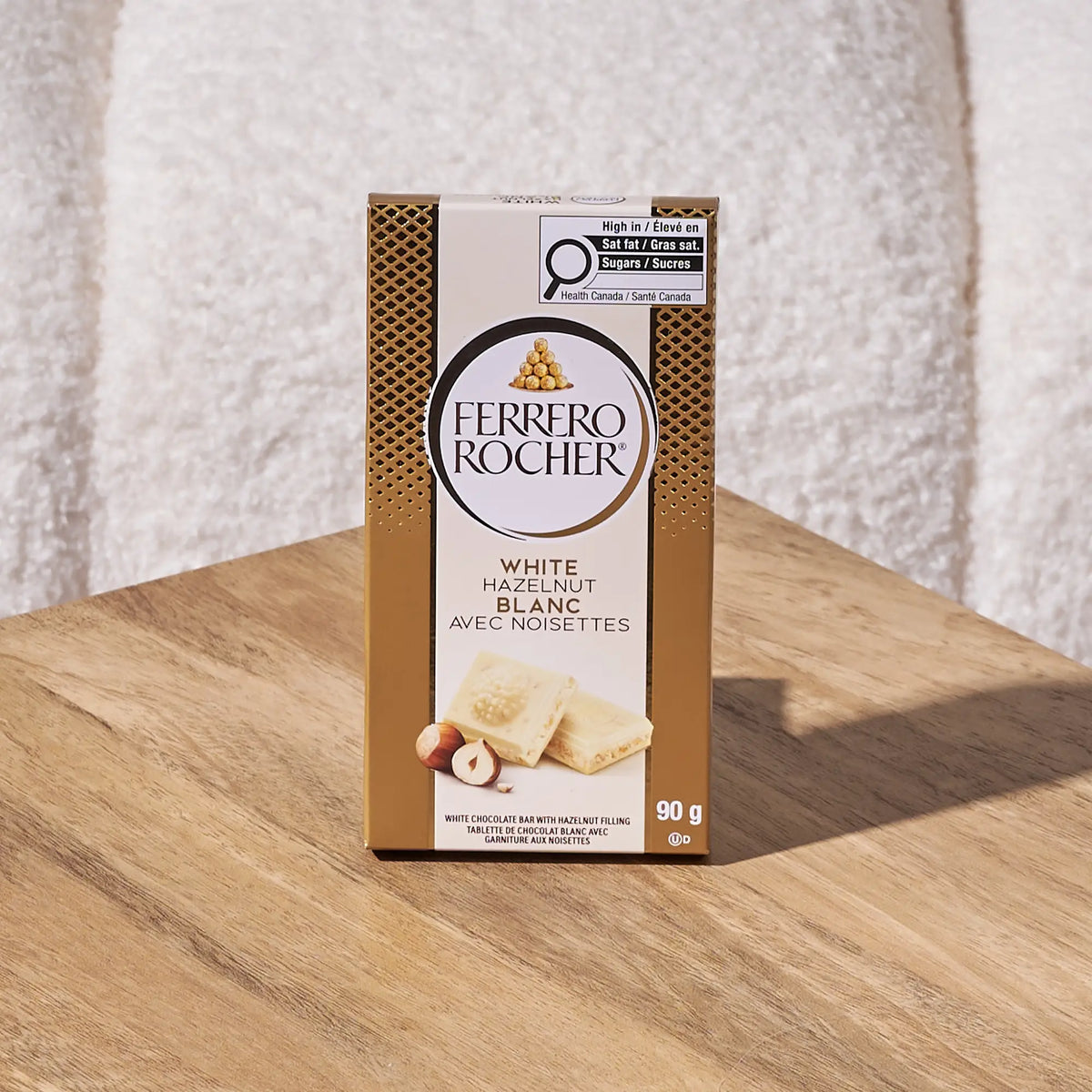 Ferrero Rocher white hazelnut chocolate box on a wooden surface with a textured white background
